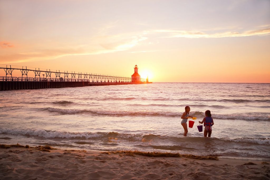 kids playing by the shore with a lighthouse